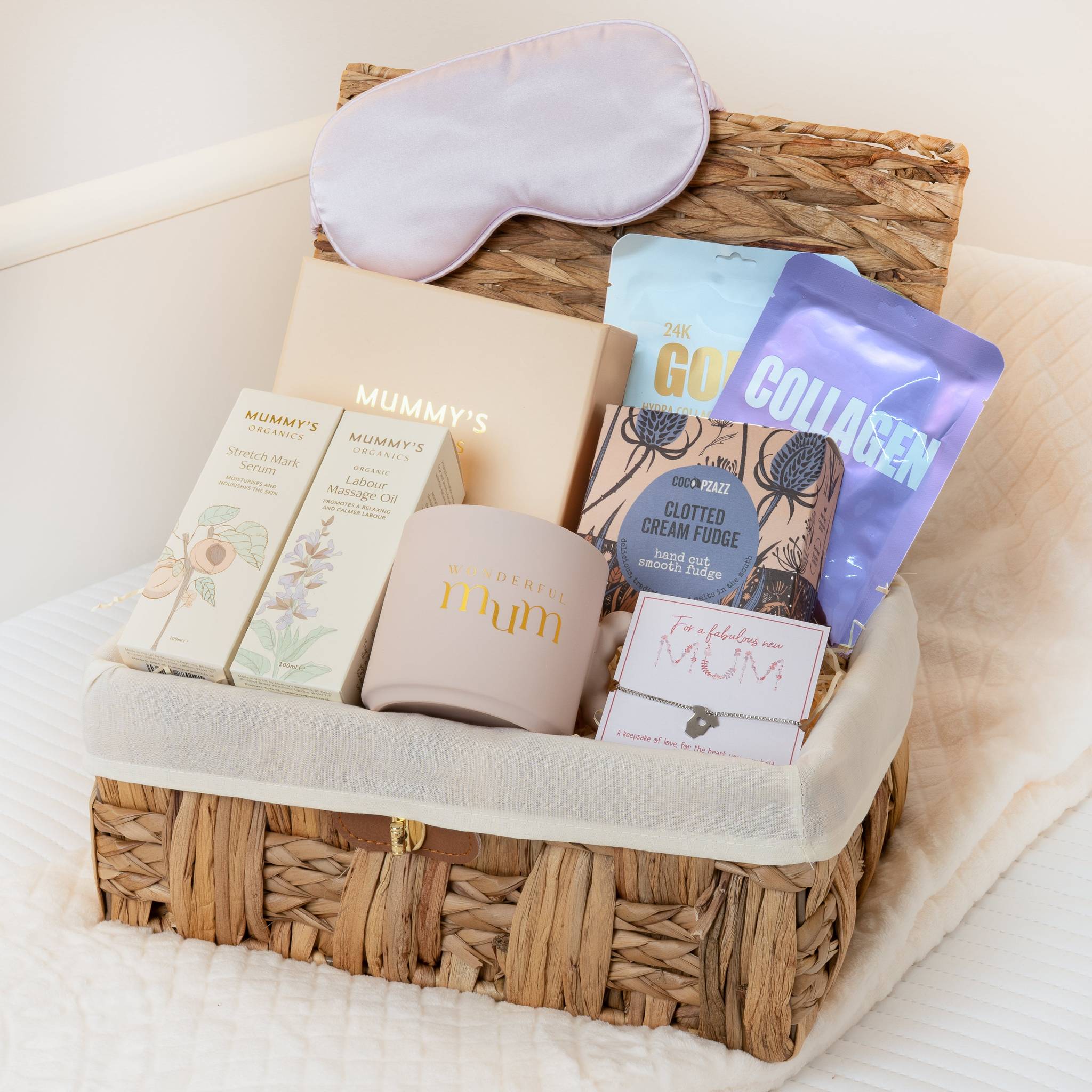 Gift basket with self-care items including a sleep mask, mug, and snacks on a white surface. Main image