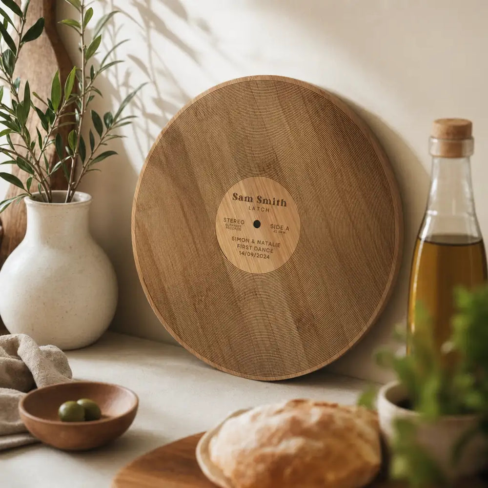 Circular wooden cutting board designed to resemble a vinyl record, featuring engraved text on its center label.