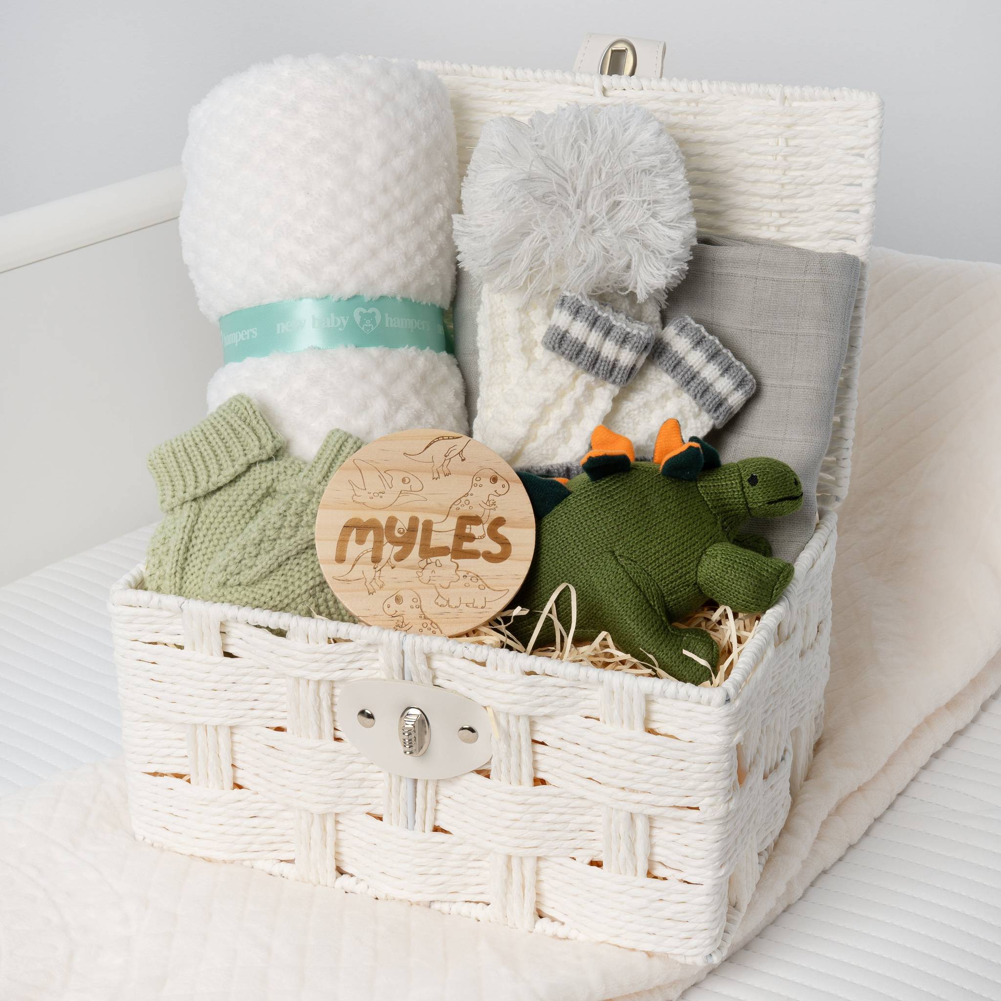 Baby gift basket with plush turtle, blanket, and knitted items on a white surface. Main image